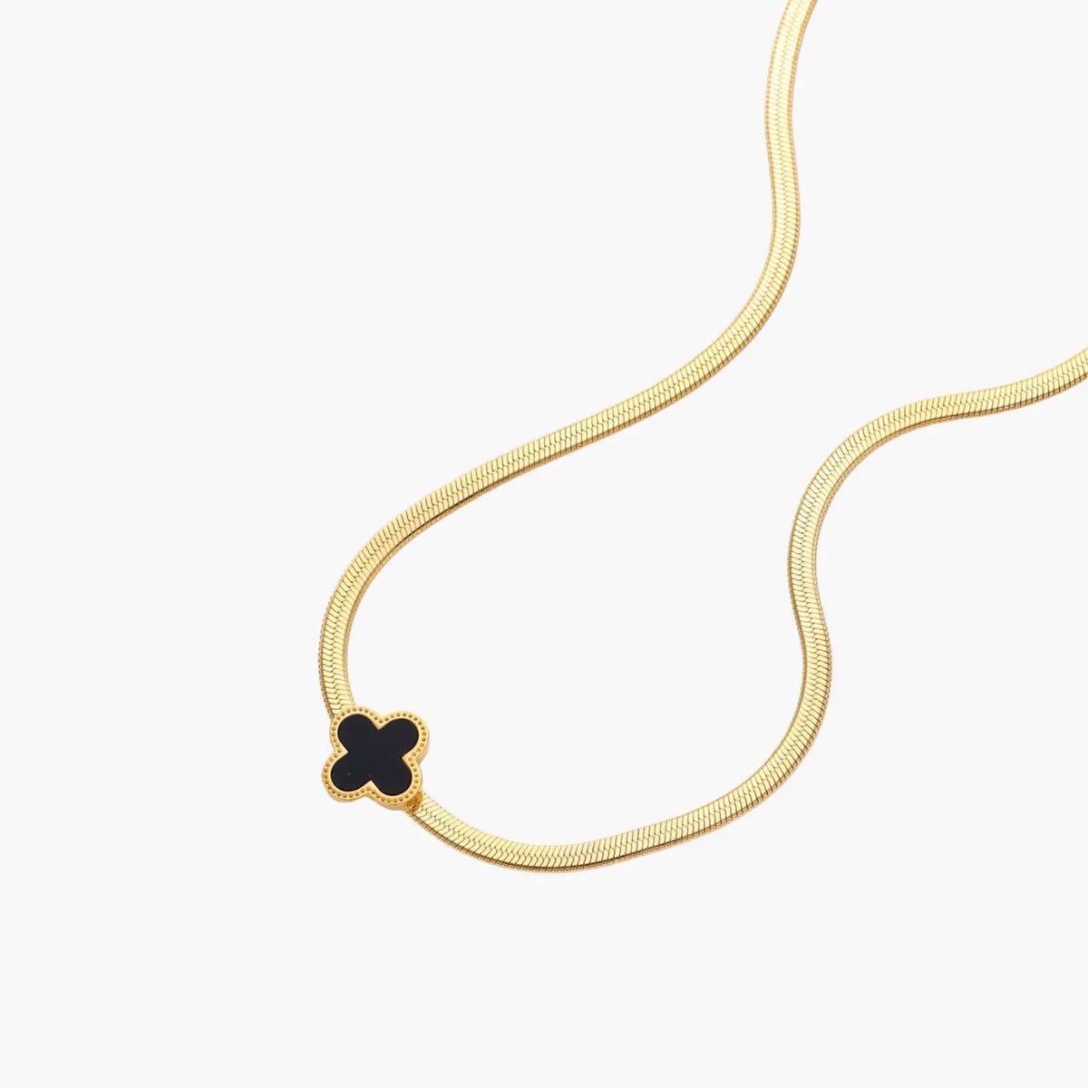 Dainty 18K gold-plated herringbone chain necklace with black enamel quatrefoil clover pendant on white background