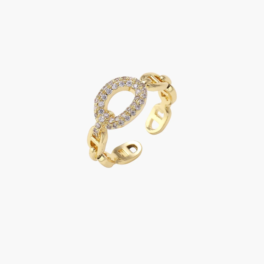 Gold-plated brass chain link ring with one oval CZ-pavÃ© segment on cream background, adjustable cuff style.