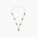 14K gold-plated necklace with eye-shaped stations and baroque pearl pendant on cream background