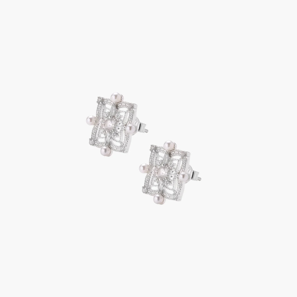 Ornate sterling silver stud earrings with mandala-inspired filigree pattern and four freshwater pearls on beige background