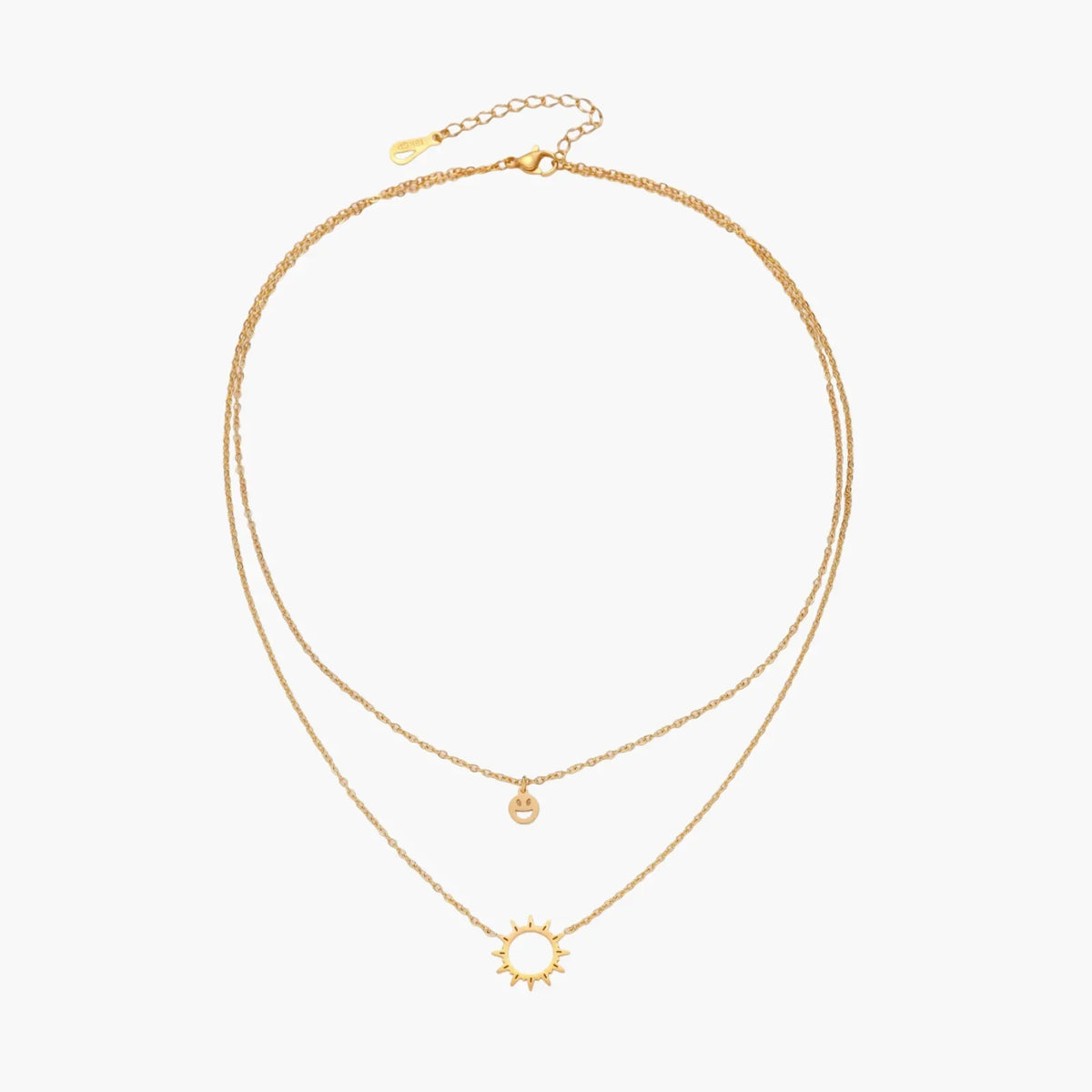 Gold layered necklace set with sunburst and smiley face pendants on delicate chains against white background.