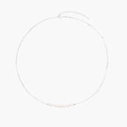 Delicate sterling silver chain necklace with small freshwater pearls arranged in a curved smile arc on cream background.