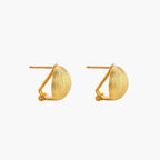 Pair of brushed gold dome earrings with clip backs showing textured matte finish on cream background