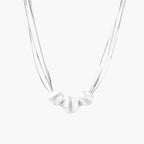 Sterling silver multi-strand necklace with three brushed round beads on cream background
