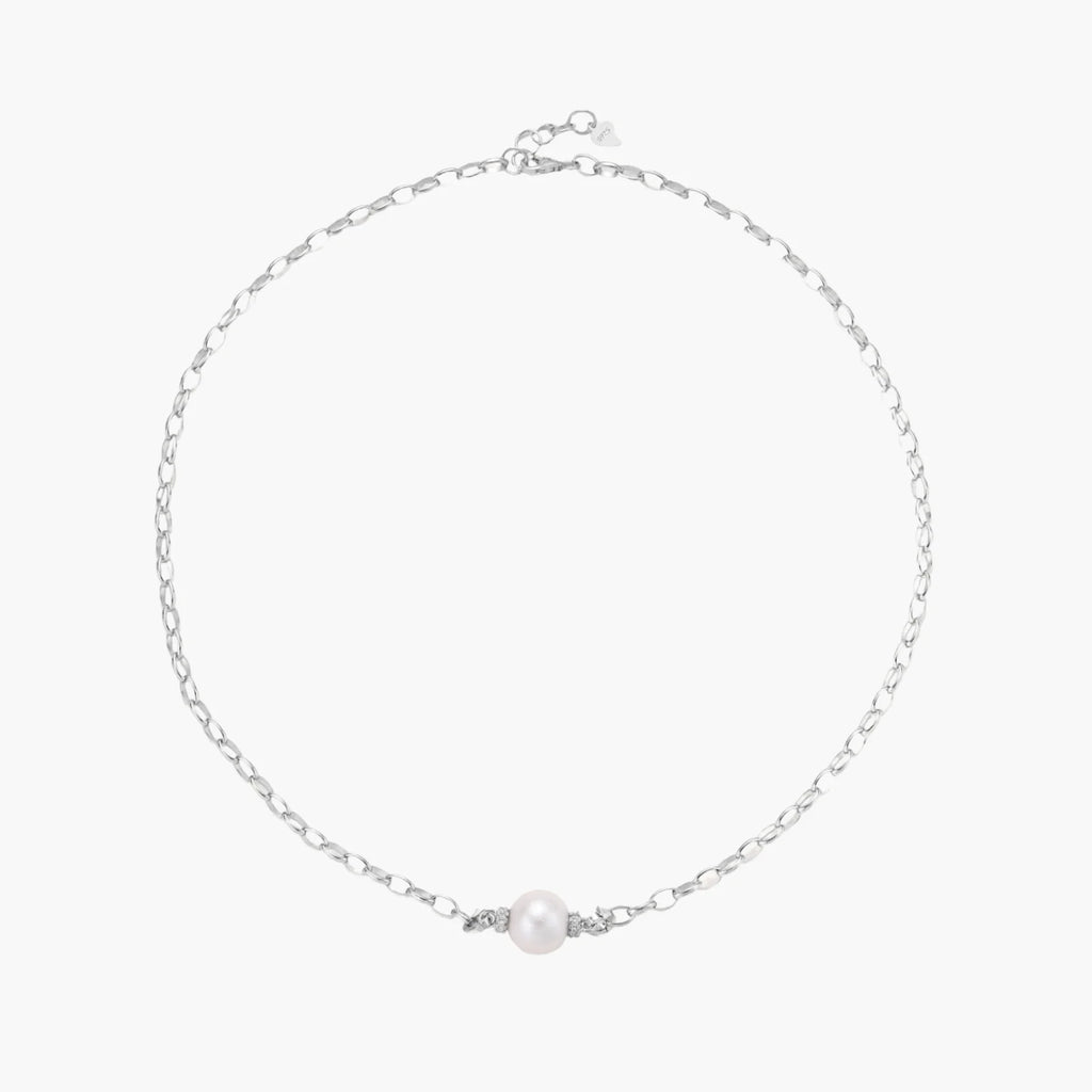 Dainty rhodium-plated silver chain necklace with centered 10mm freshwater pearl and crystal accents on cream background